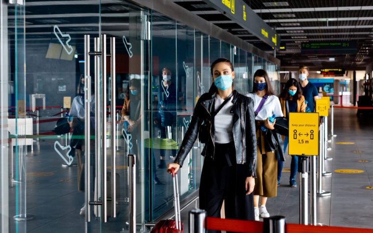 Passengers standing in line at an airport with facemasks on
