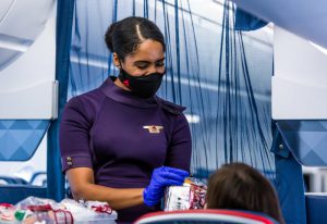 An Delta cabin crew member hands out snacks onboard a flight