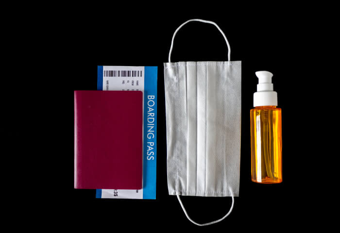 A passport, boarding pass, face mask and spray bottle