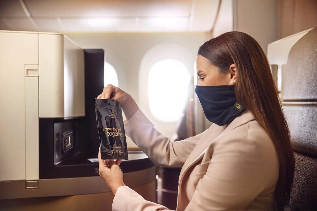 A woman wears a new Etihad Microbarrier facemask while sitting onboard a plane