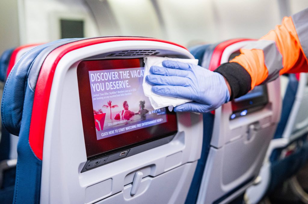 A worker wipes the seat back screen onboard an airplane seat