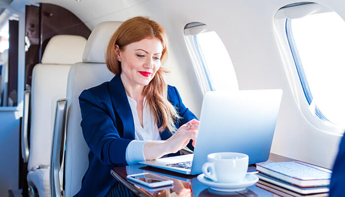 A woman types on a laptop aboard a business jet