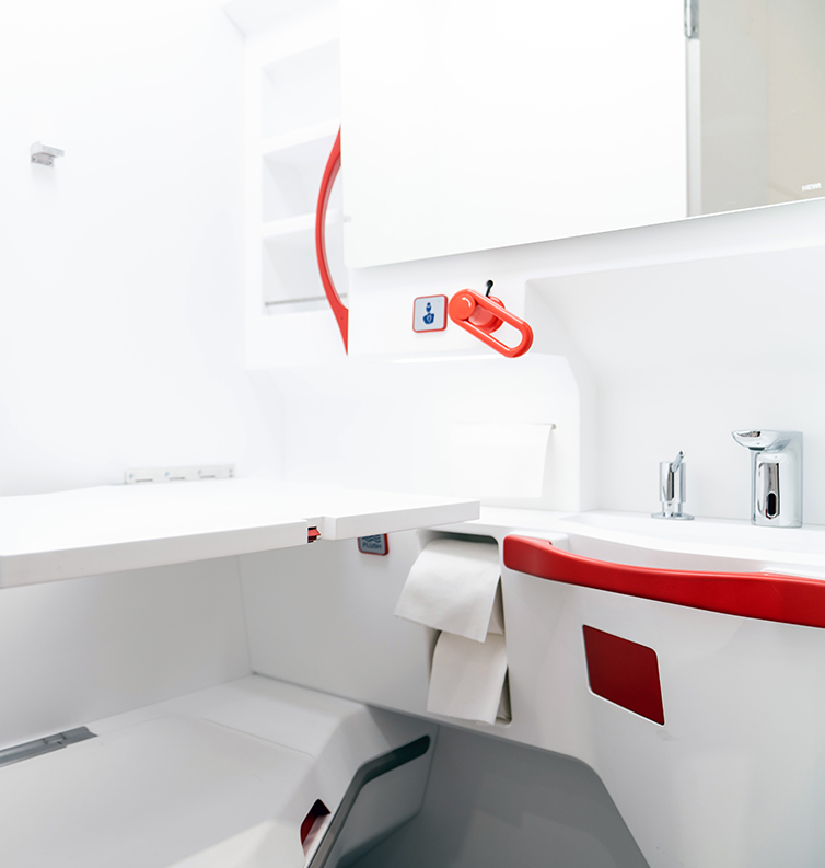 Interior of an airline lavatory with bright red handles.