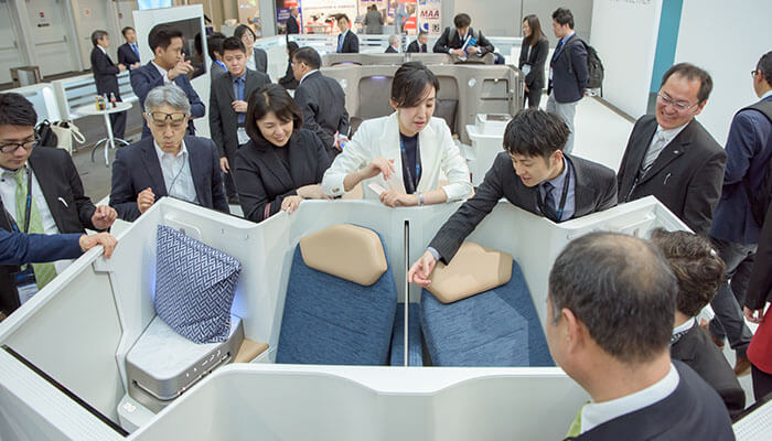 Several people look at an aircraft seating arrangement.