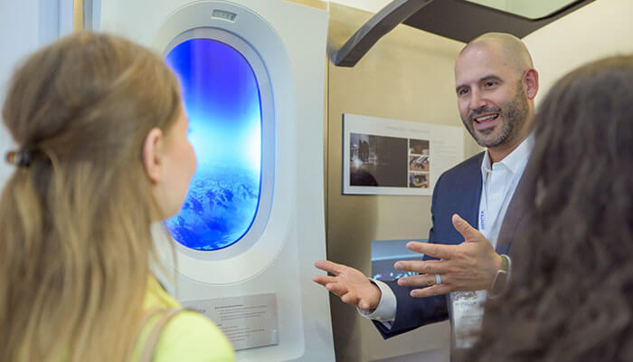 A person talks to two other people at Aircraft Interiors Expo