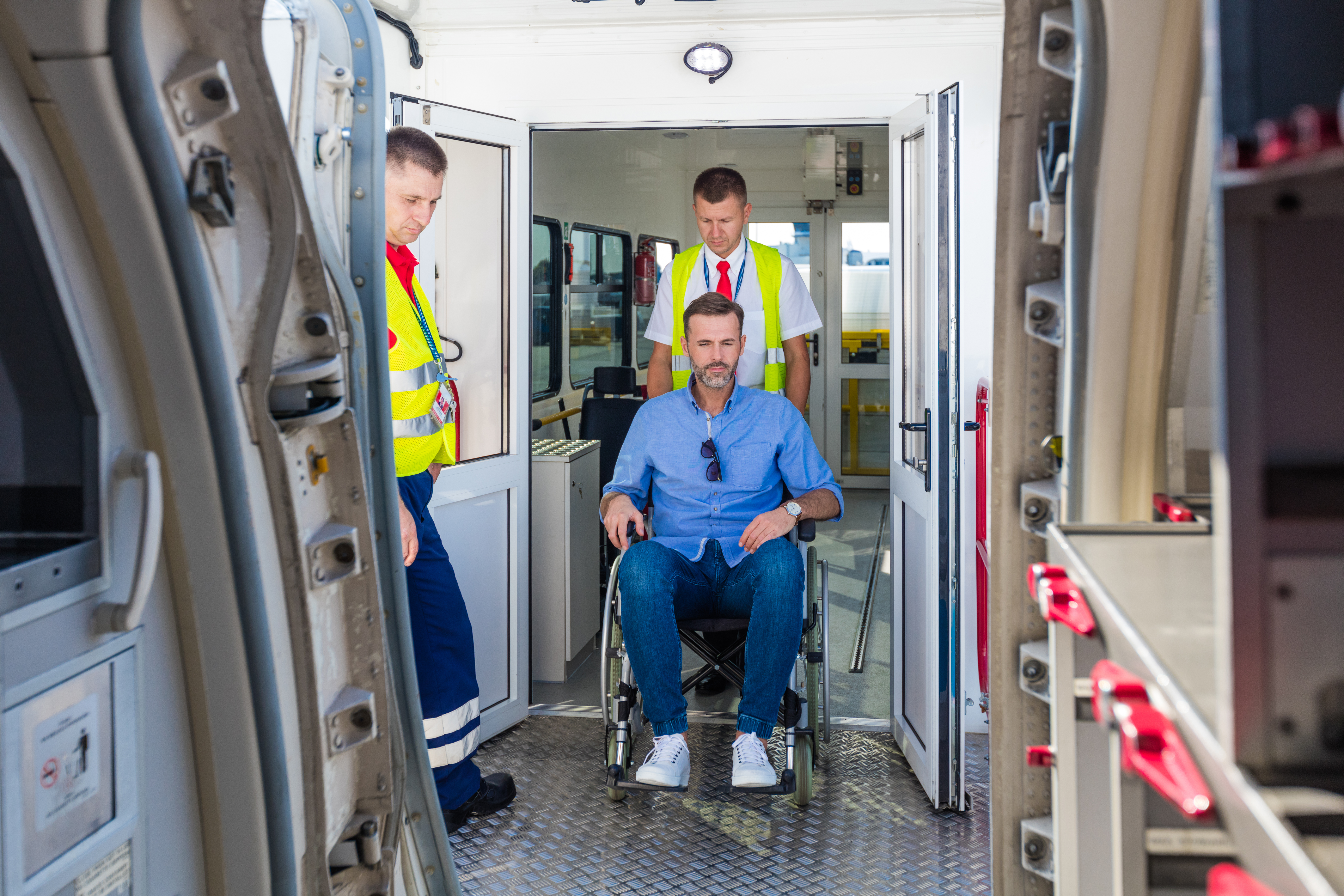 Service man helping disabled passenger to enter on board at airport