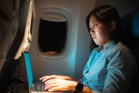 woman on desktop computer in airplane cabin