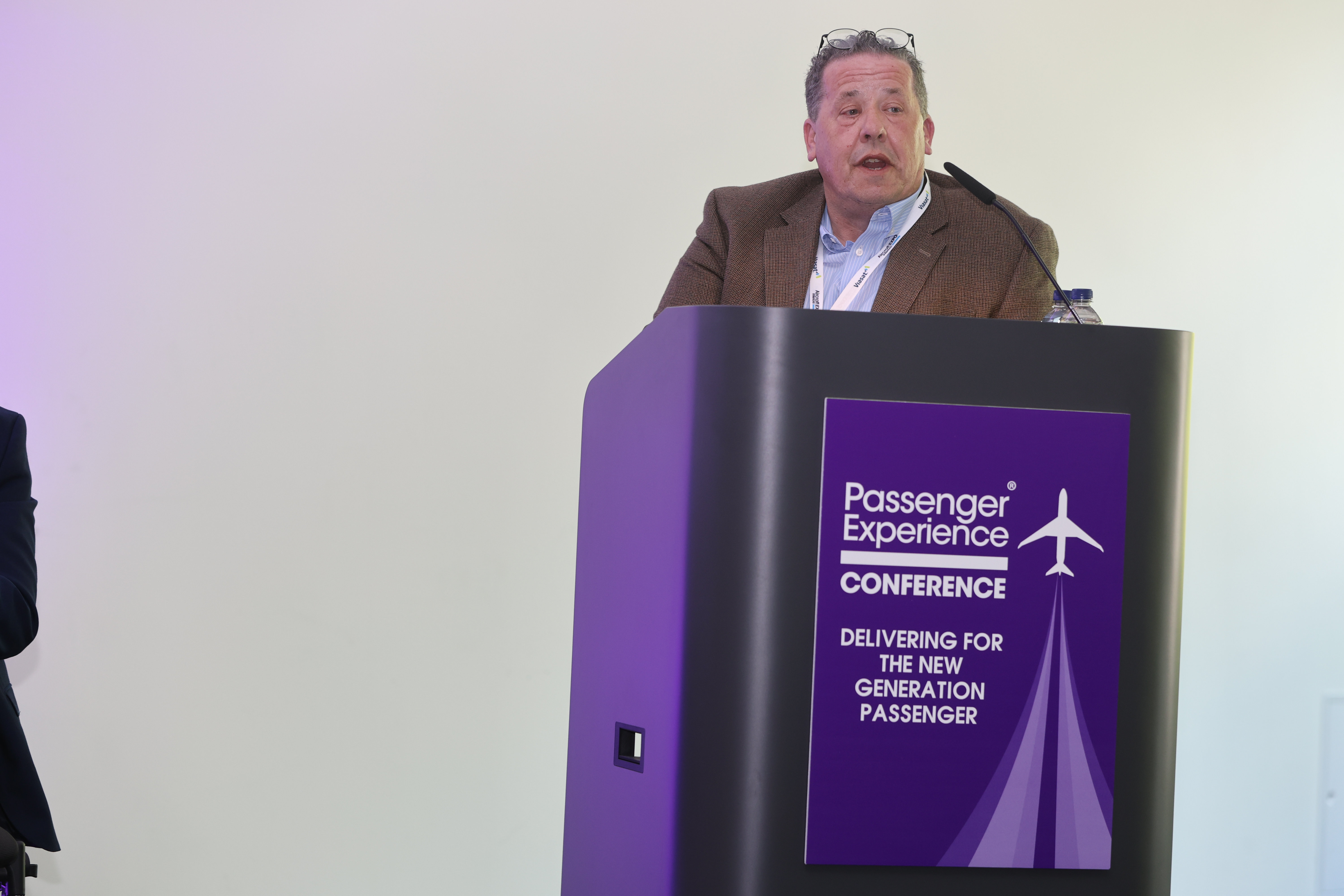 Chris Wood MBE stood behind passenger experience conference podium