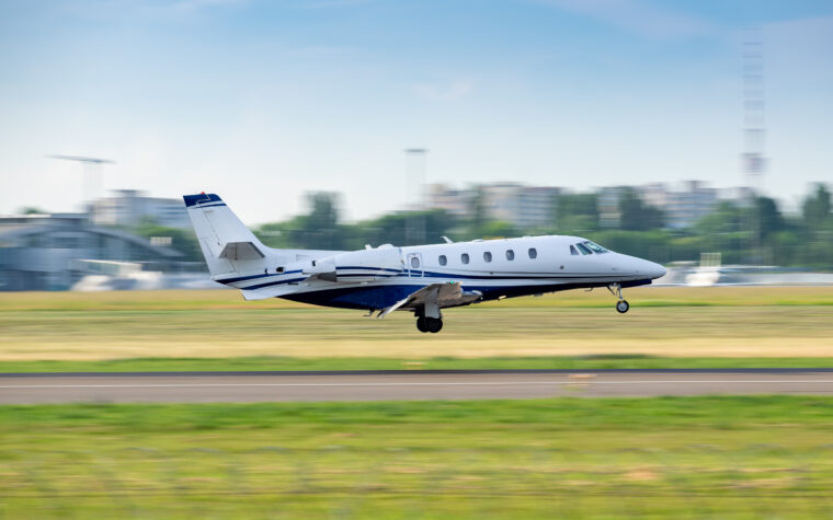 Small private business jet landing in the city airport - panning shot with blurry background
