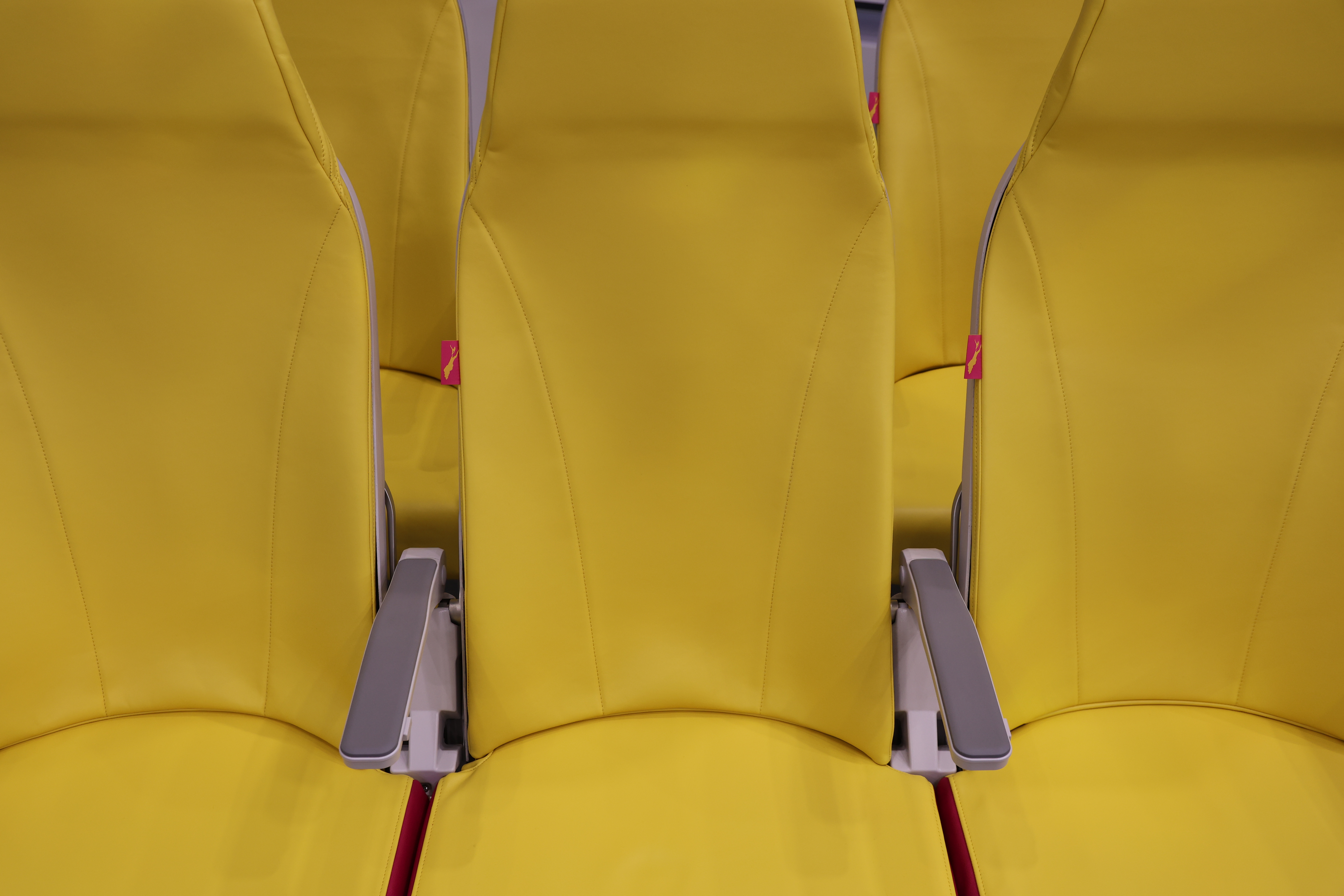 row of three airplane seats in yellow covering