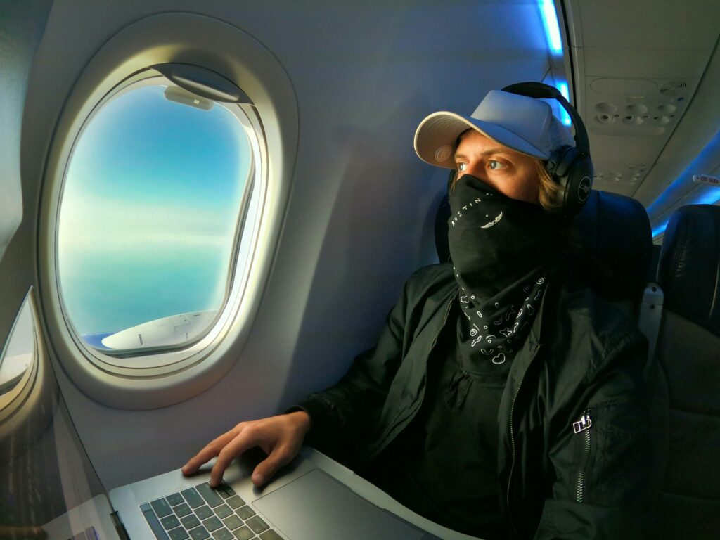 man using laptop and headphones on plane