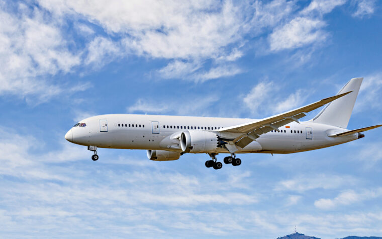 Boeing 787-8 Dreamliner passenger plane landing at the airport, under a blue sky with white clouds
